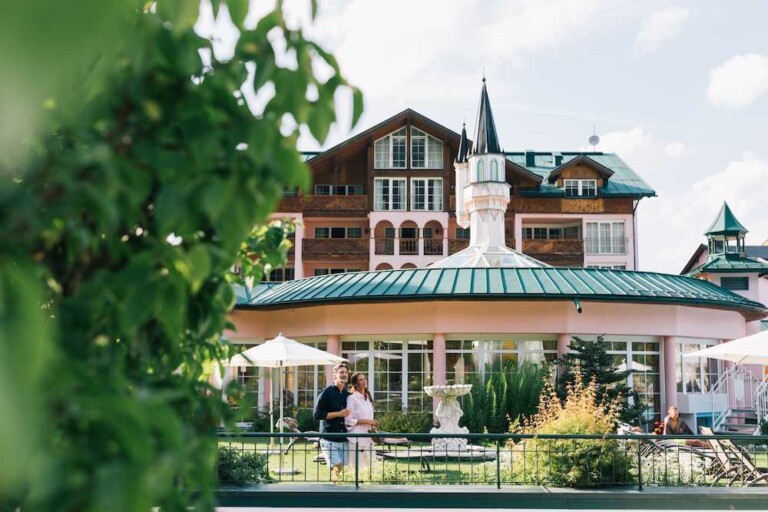 Zwei Gäste auf der Terrasse des Hotels ...liebes Rot-Flüh im Tannheimer Tal, umrahmt von sommerlichem Grün.