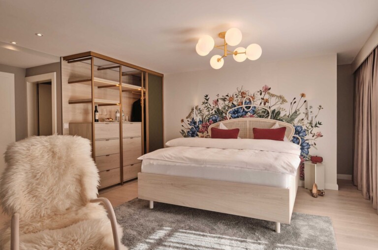 Helles Zimmer im Hotel ...liebes Rot-Flüh mit floraler Wandbemalung, modernem Kleiderschrank und Fellsessel.