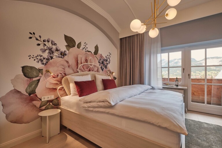 Romantisches Zimmer im Hotel ...liebes Rot-Flüh mit floraler Wandbemalung, goldenem Kronleuchter und Balkonblick.