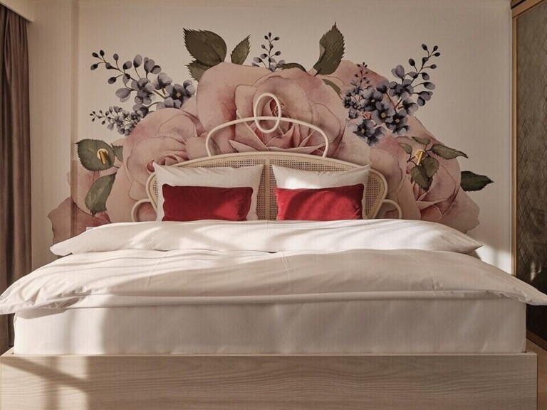 Bett im Hotel ...liebes Rot-Flüh mit Rattankopfteil, roten Kissen und großflächiger floraler Wandbemalung.