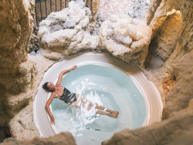 Frau entspannt in einem Whirlpool umgeben von einer Steingrotte im Wellnesshotel ...liebes Rot-Flüh.