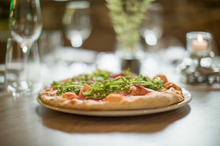 Frisch zubereitete Pizza mit Rucola im Restaurant in Grän im Tannheimer Tal.