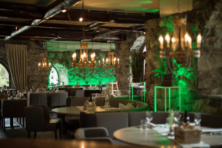 Stimmungsvolles Restaurant im ...liebes Rot-Flüh in Grän mit Steinwänden, Kerzenleuchtern und grüner Beleuchtung.