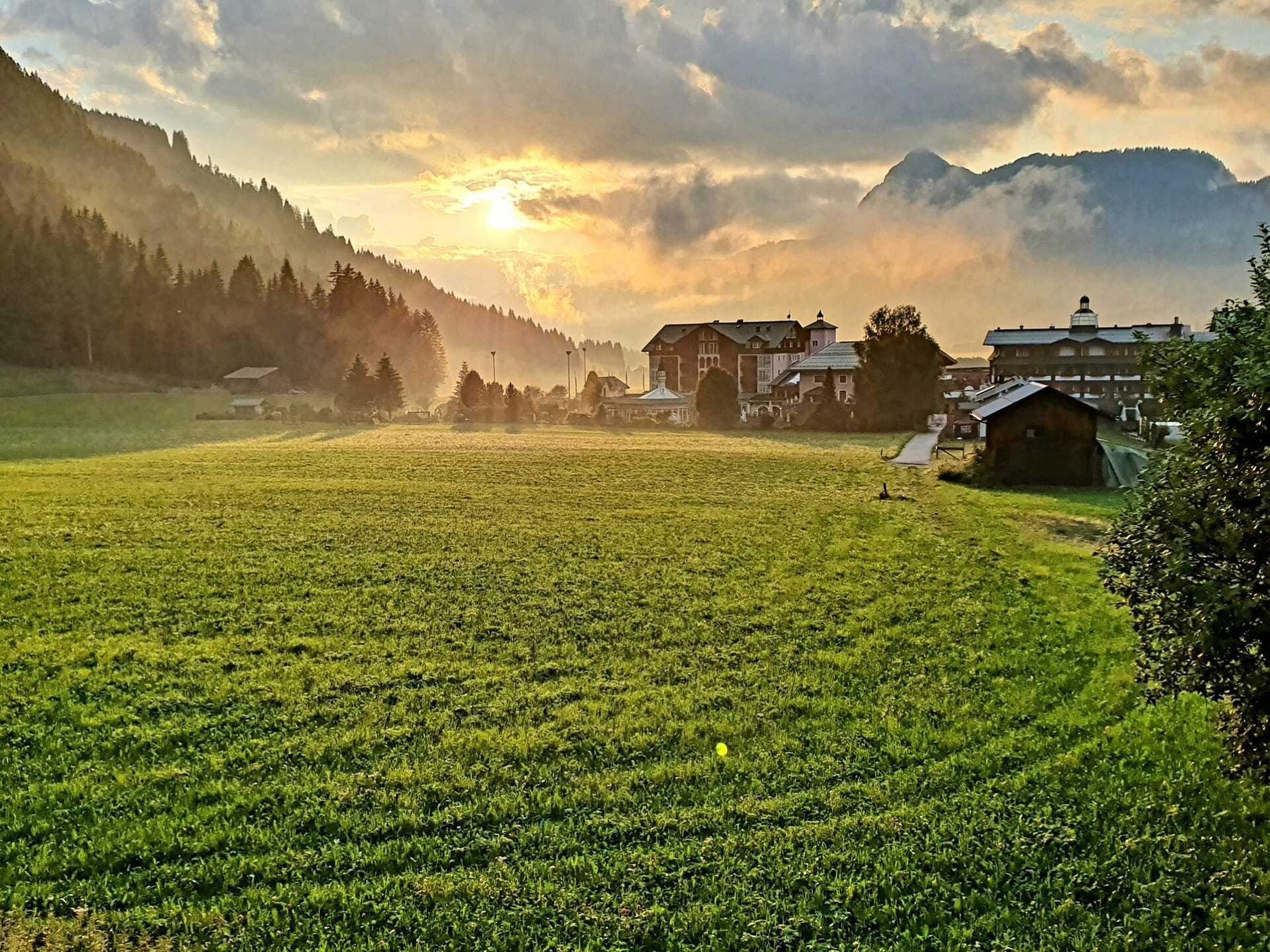 Sonnenaufgang im Tannheimer Tal mit Blick auf eine grüne Wiese und das Hotel ...liebes Rot-Flüh.