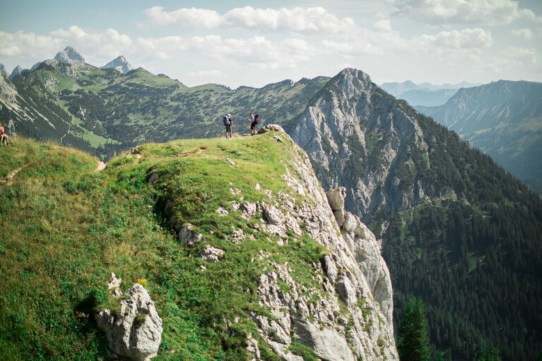 Wanderung auf einen begrünten Felsen mit zwei Personen auf dem Gipfel im Tannheimer Tal.