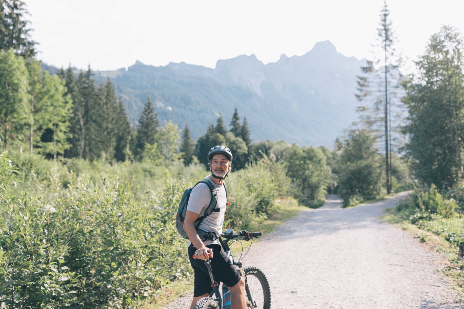 Mountainbiker auf einem Waldweg mit Bergen im Hintergrund im Tannheimer Tal.