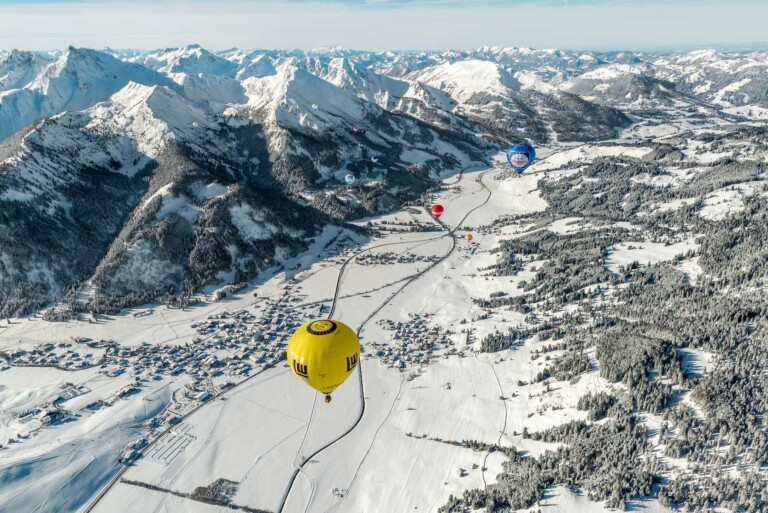 Zwei Heißluftballons fliegen über das Tannheimer Tal mit Blick auf die Berge.