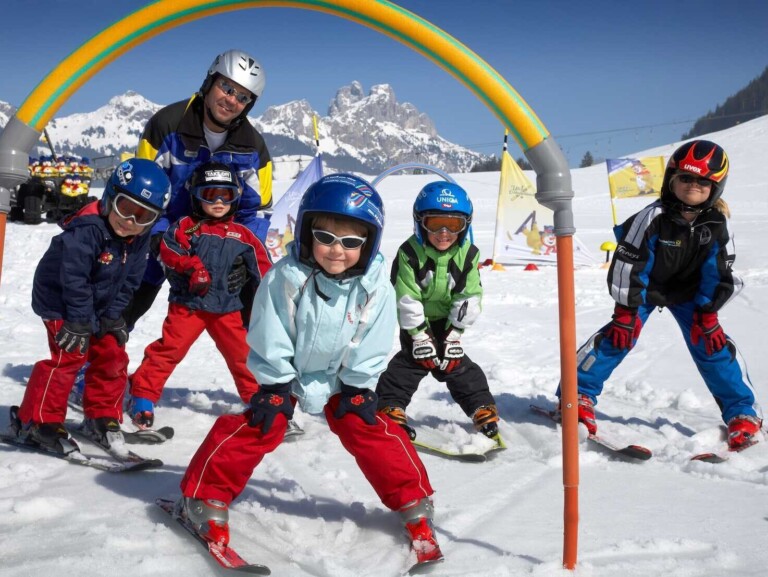 Kinder im Skikurs mit einem Skilehrer im Familienurlaub im Tannheimer Tal.