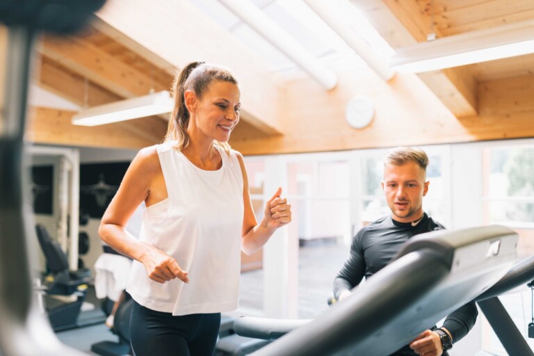 Fitnesstrainer mit Frau auf dem Laufband im ...liebes Rot-FLüh Fitness Hotel in Österreich.