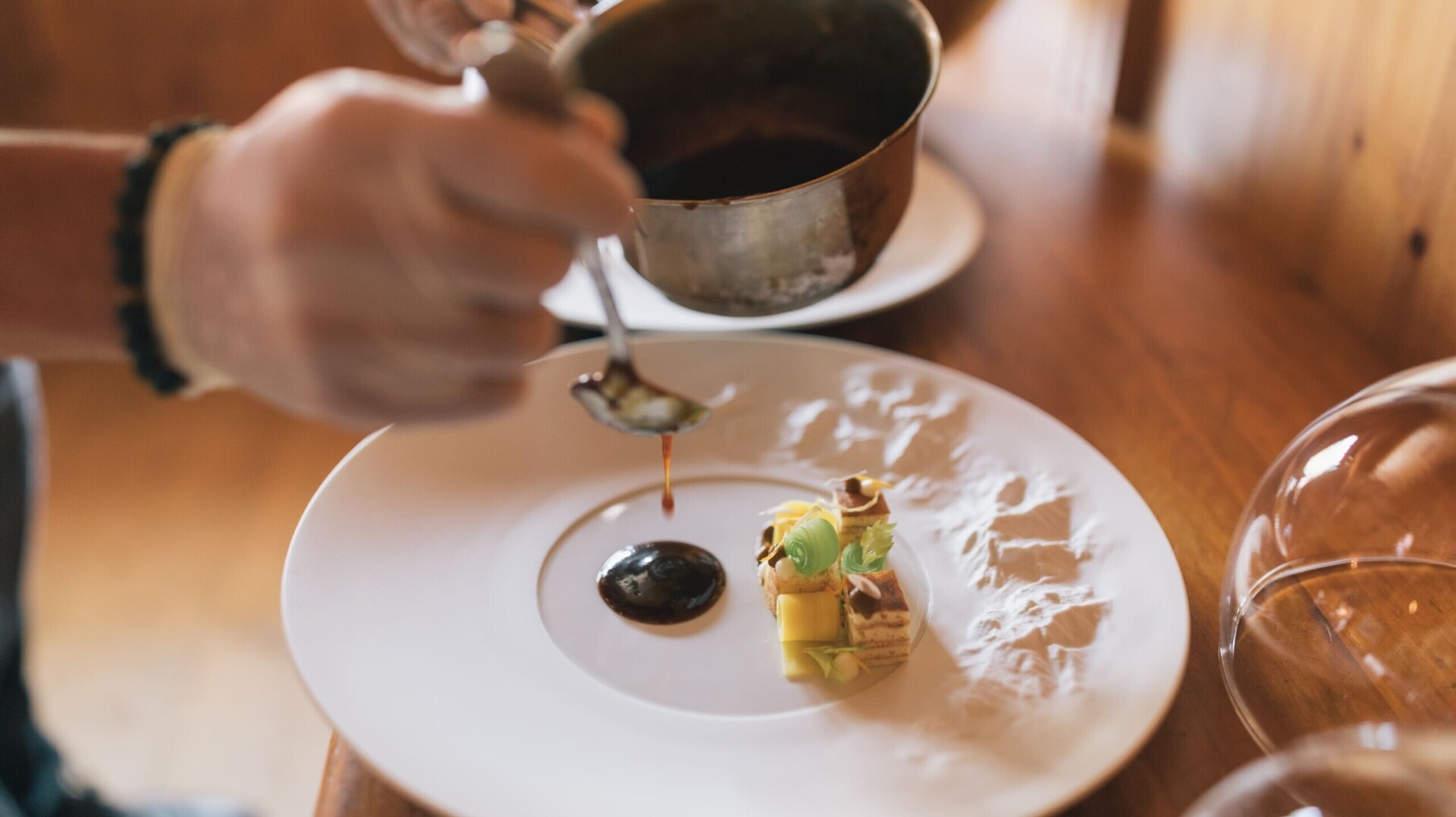 Koch richtet Gericht mit Soße an im Gourmetrestaurant ...liebes Rot-Flüh in Tirol.