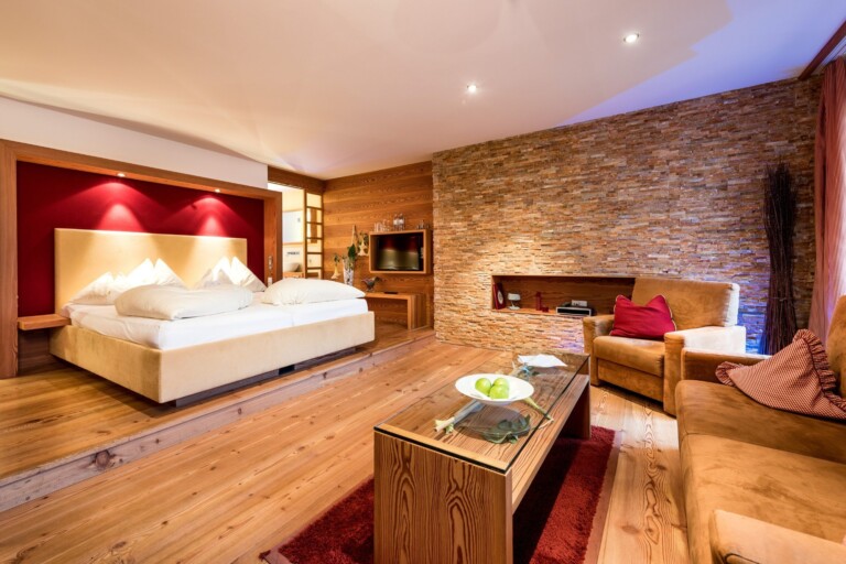 Suite mit Steinwand und roter Rückwand am Bett im ...liebes-Rot-Flüh.